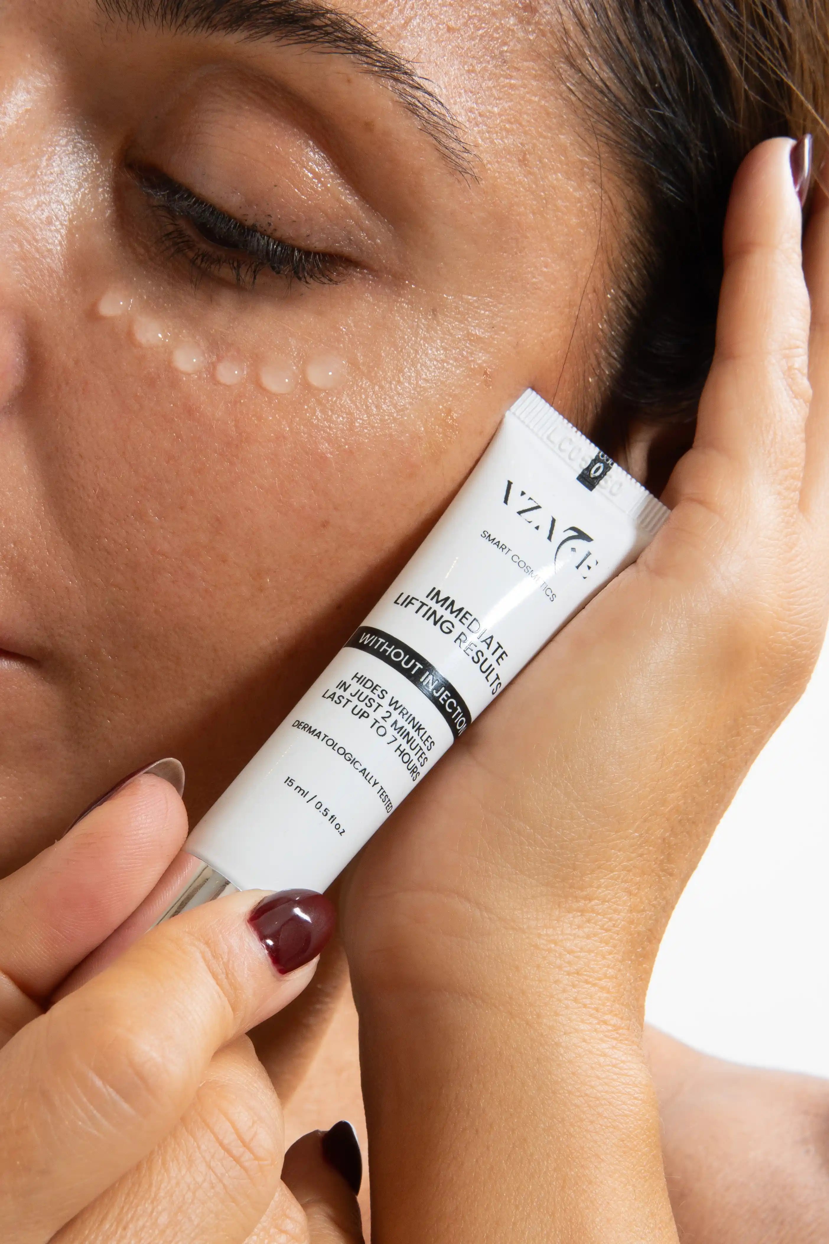 Person applying a skincare product to their face with a close-up of the product tube.